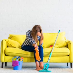 frustrated-young-woman-sitting-sofa-with-cleaning-equipments_23-2147916459